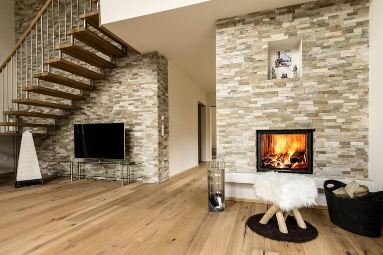 Wohnzimmer mit moderner Natursteinwand und Kamin in Oberaudorf
